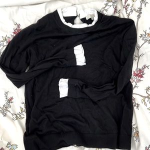 Light weight fitted black sweater with white ruffles at neck and sleeve